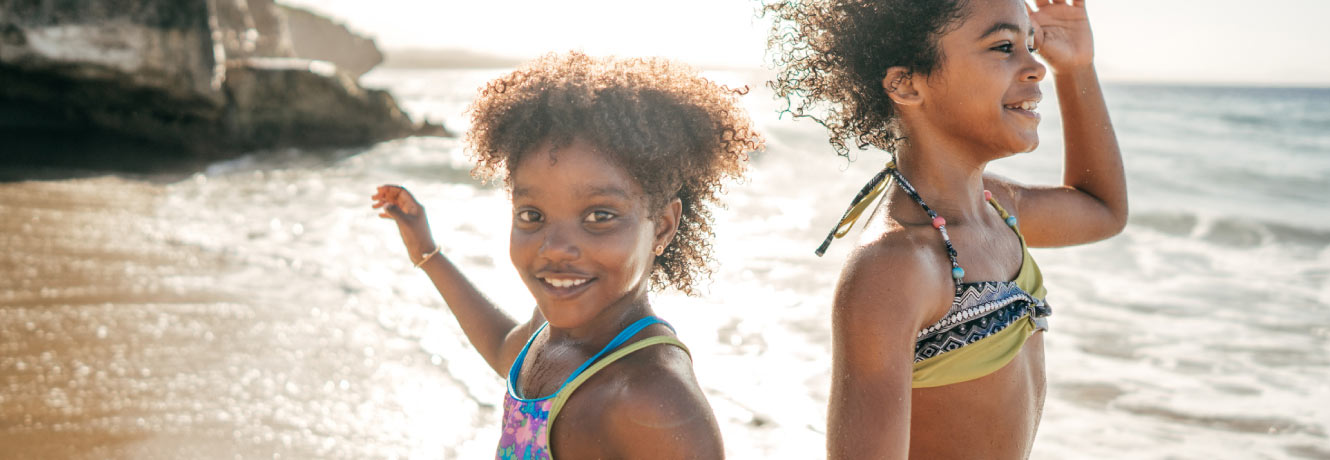 Two young girls play joyfully on the beach.