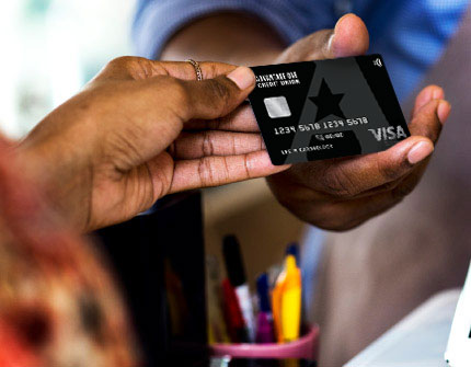 A close-up view of an AOCU credit card exchanging hands during a payment interaction.